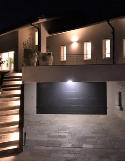 Facciata abitazione con illuminazione architettonica serale, esempio di finiture esterne in ristrutturazione edilizia.