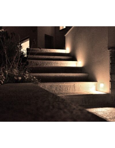 Scala esterna illuminata con faretti a incasso su parete in pietra, dettaglio architettonico di finitura per edificio residenziale.