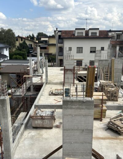 Struttura verticale in cemento armato durante fase di realizzazione, con gru e cantiere attivo sullo sfondo.