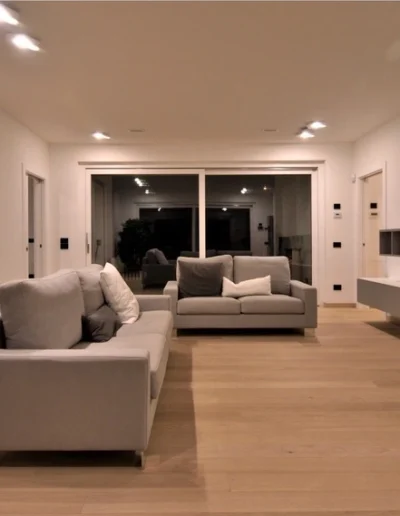 Salotto moderno con finiture di pregio e illuminazione integrata, esempio di ristrutturazione interna di abitazione.