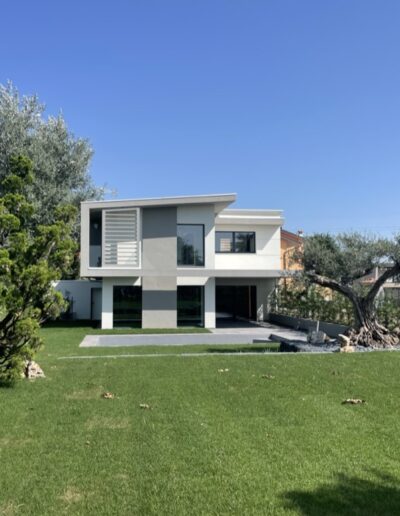 Abitazione unifamiliare moderna con ampio giardino verde, esempio di nuova costruzione residenziale.