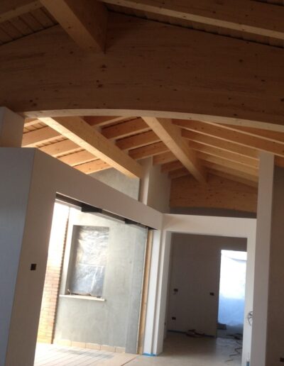 Interno sottotetto con travi in legno a vista, esempio di ristrutturazione o recupero abitativo mansardato.