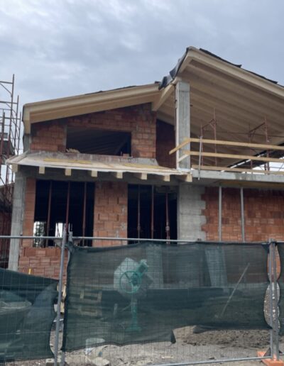 Edificio residenziale in costruzione con ponteggi e struttura in muratura visibile, lavori in corso su nuova abitazione.