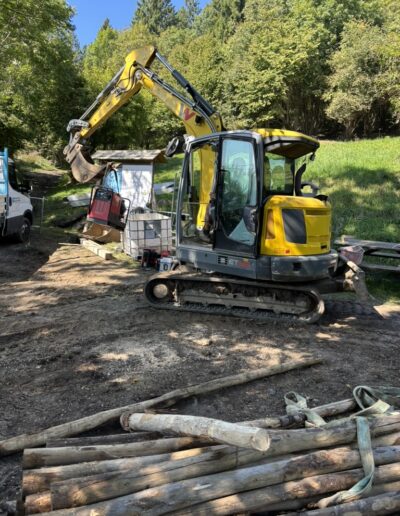 Escavatore giallo impegnato in lavori di scavo e movimento terra su terreno destinato a nuova costruzione.